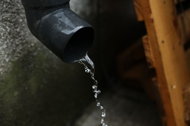 Photo of Water flowing from drain pipe outdoors, closeup