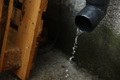 Photo of Water flowing from drain pipe outdoors, closeup