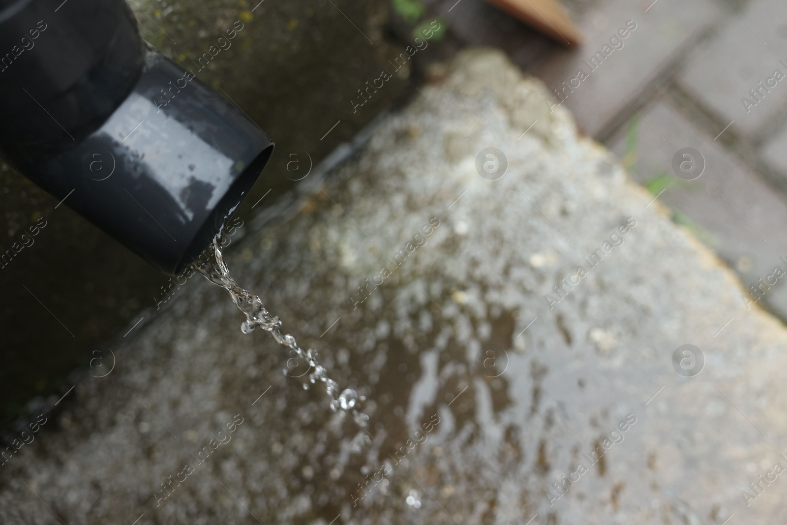 Water dripping from drain pipe outdoors, above view. Space for text Photo of Water dripping from drain pipe outdoors, above view. Space for text