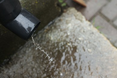Photo of Water dripping from drain pipe outdoors, above view. Space for text