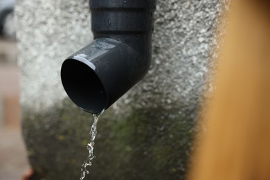 Photo of Water dripping from drain pipe outdoors, closeup