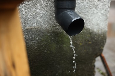 Photo of Water dripping from drain pipe outdoors, closeup
