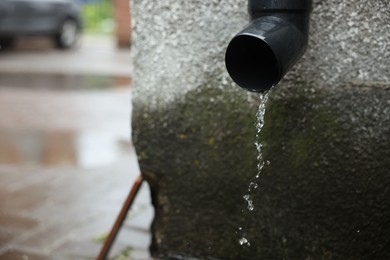 Photo of Water dripping from drain pipe outdoors, closeup. Space for text