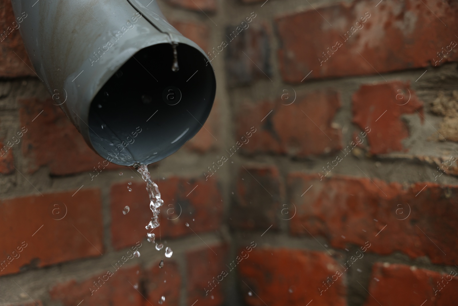 Water dripping from drain pipe outdoors, closeup. Space for text Photo of Water dripping from drain pipe outdoors, closeup. Space for text