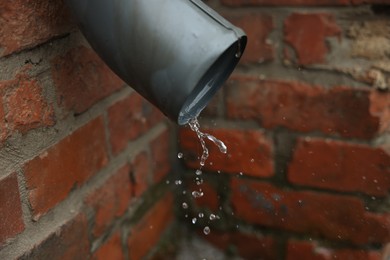 Photo of Water dripping from drain pipe outdoors, closeup