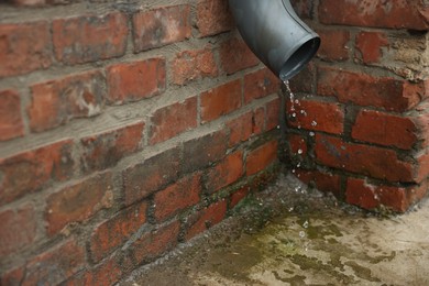 Photo of Water dripping from drain pipe outdoors, closeup