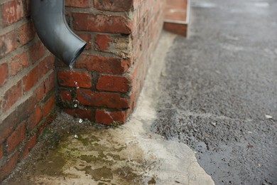 Photo of Water dripping from drain pipe outdoors, closeup. Space for text