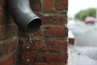 Photo of Water dripping from drain pipe outdoors, closeup
