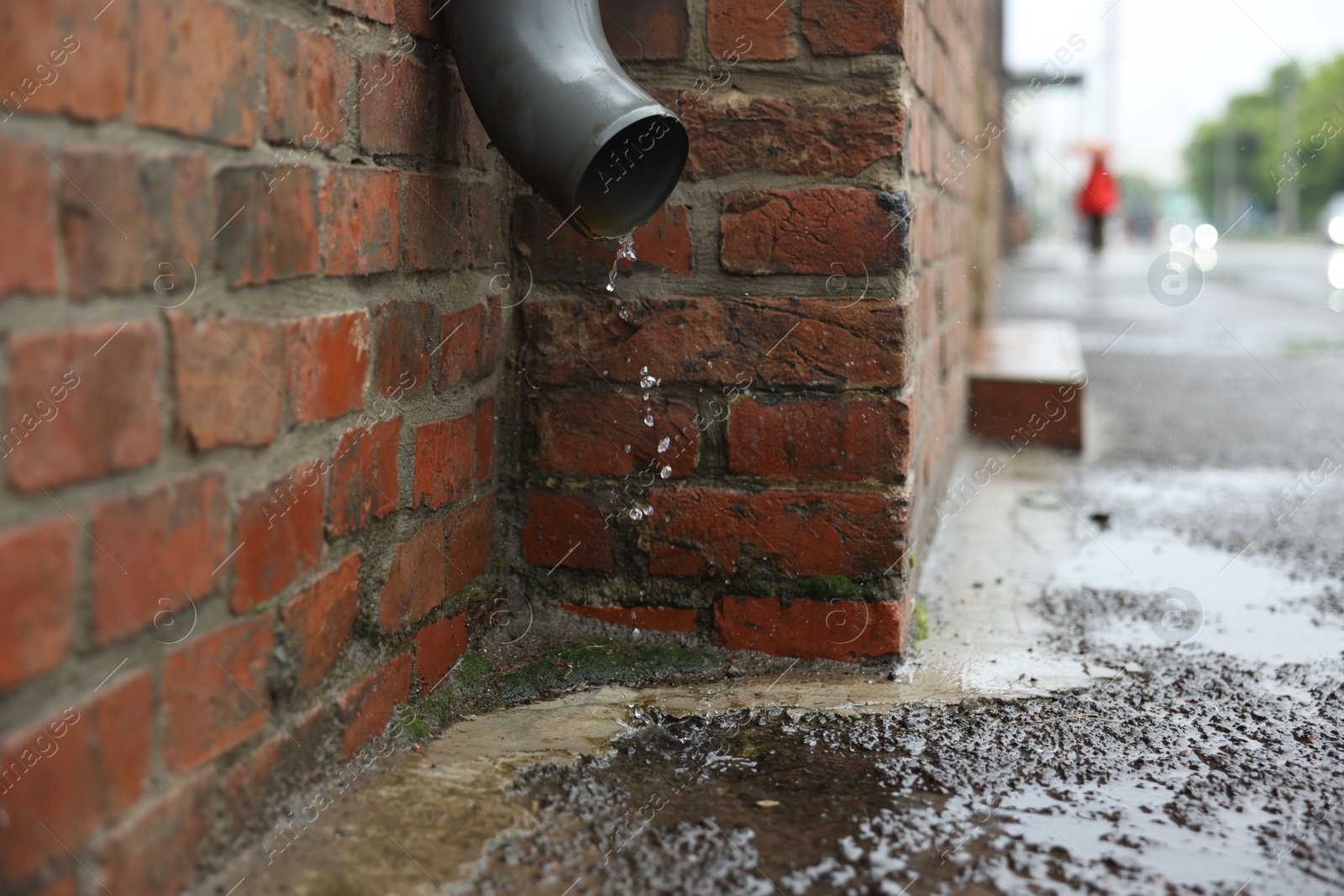 Water dripping from drain pipe outdoors, space for text Photo of Water dripping from drain pipe outdoors, space for text