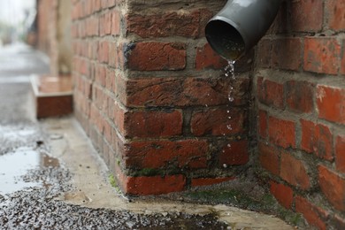 Photo of Water dripping from drain pipe outdoors, space for text