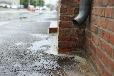 Photo of Water dripping from drain pipe outdoors, space for text