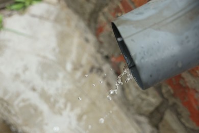 Photo of Water dripping from drain pipe outdoors, above view. Space for text