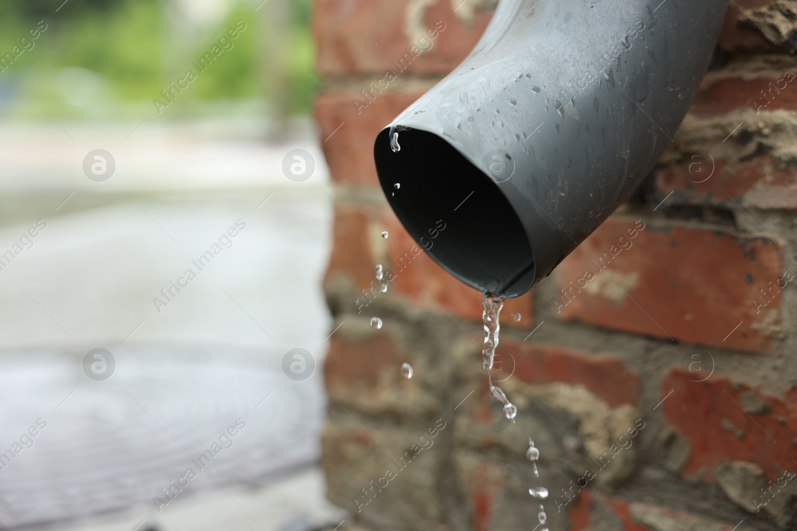 Water dripping from drain pipe outdoors, closeup. Space for text Photo of Water dripping from drain pipe outdoors, closeup. Space for text