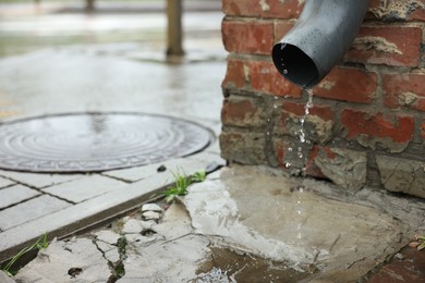 Photo of Water dripping from drain pipe outdoors, space for text