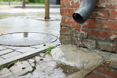 Photo of Water dripping from drain pipe outdoors, space for text
