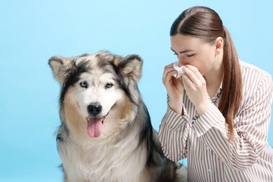 Photo of Woman suffering from allergy with her dog on light blue background