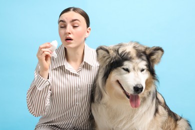 Photo of Woman suffering from allergy with her dog on light blue background