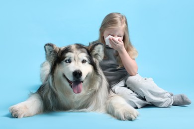 Photo of Girl suffering from allergy with her dog on light blue background
