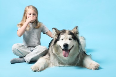 Photo of Girl suffering from allergy with her dog on light blue background