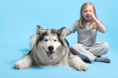 Photo of Girl suffering from allergy with her dog on light blue background