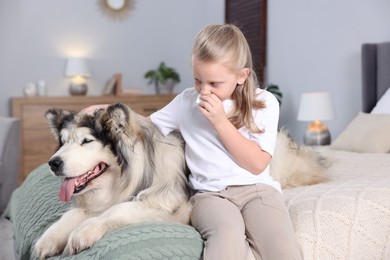 Photo of Girl suffering from allergy with her dog on bed at home