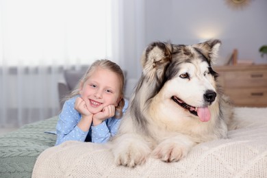 Photo of Little girl and cute dog on bed at home
