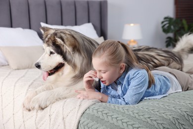 Photo of Girl suffering from allergy with her dog on bed at home