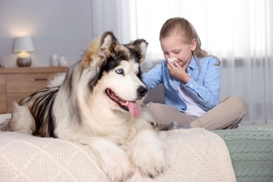 Photo of Girl suffering from allergy with her dog on bed at home