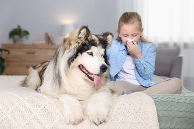 Photo of Girl suffering from allergy with her dog on bed at home