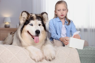 Photo of Girl suffering from allergy with her dog on bed at home