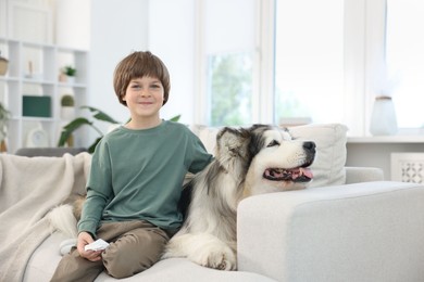 Photo of Happy boy and cute dog on sofa at home