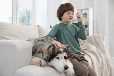 Photo of Boy suffering from allergy with her dog on sofa at home