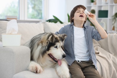 Photo of Boy suffering from allergy with her dog on sofa at home