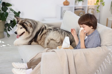 Photo of Boy suffering from allergy with her dog on sofa at home