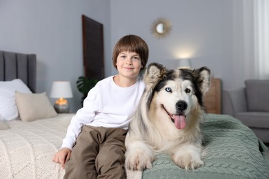 Photo of Happy boy and cute dog on bed at home