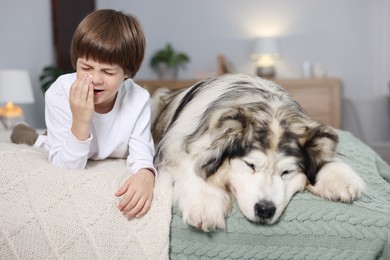 Photo of Boy suffering from allergy with her dog on bed at home
