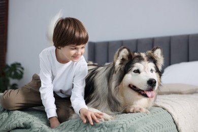 Photo of Happy boy and cute dog on bed at home