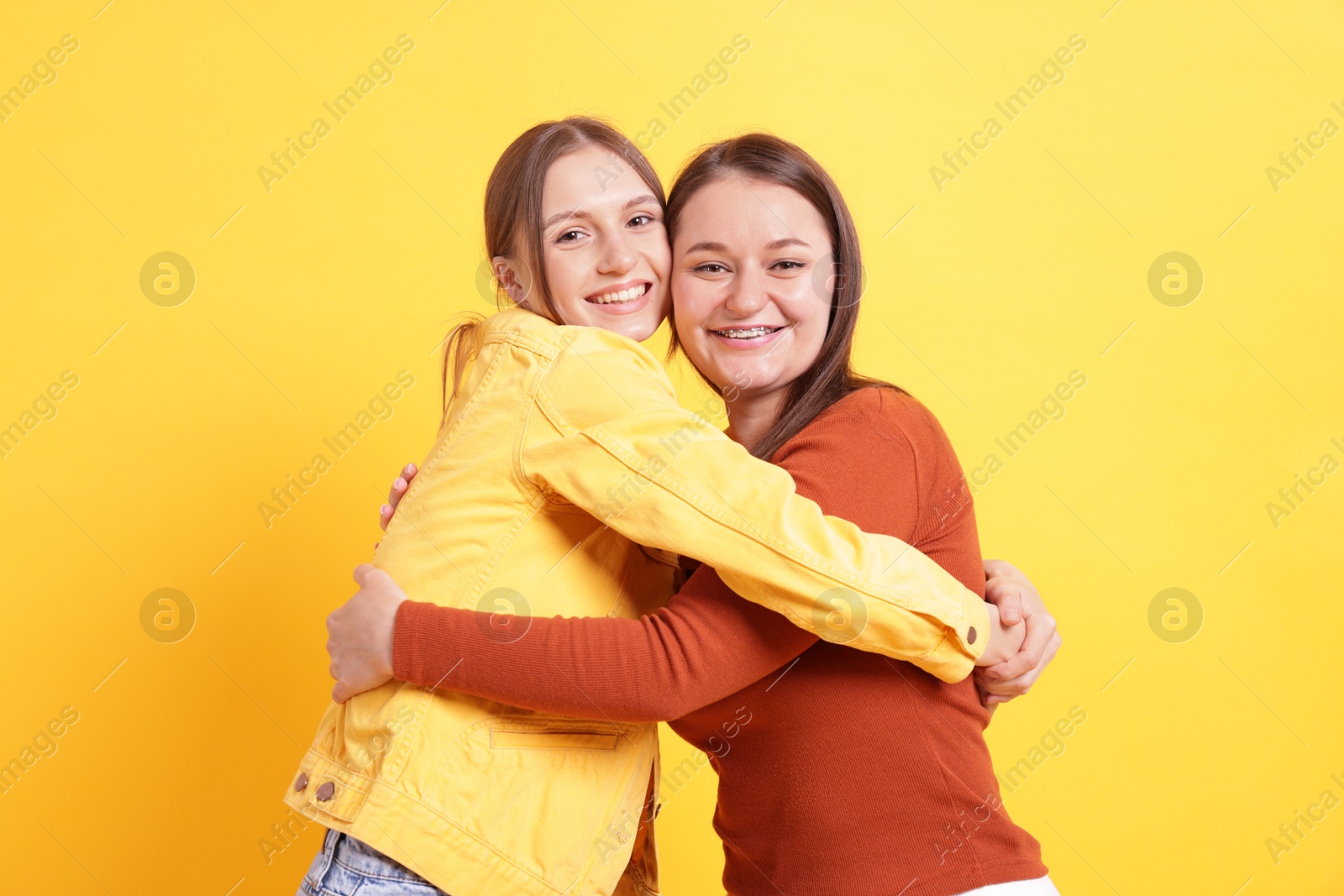 Friends hugging each other on orange background Photo of Friends hugging each other on orange background