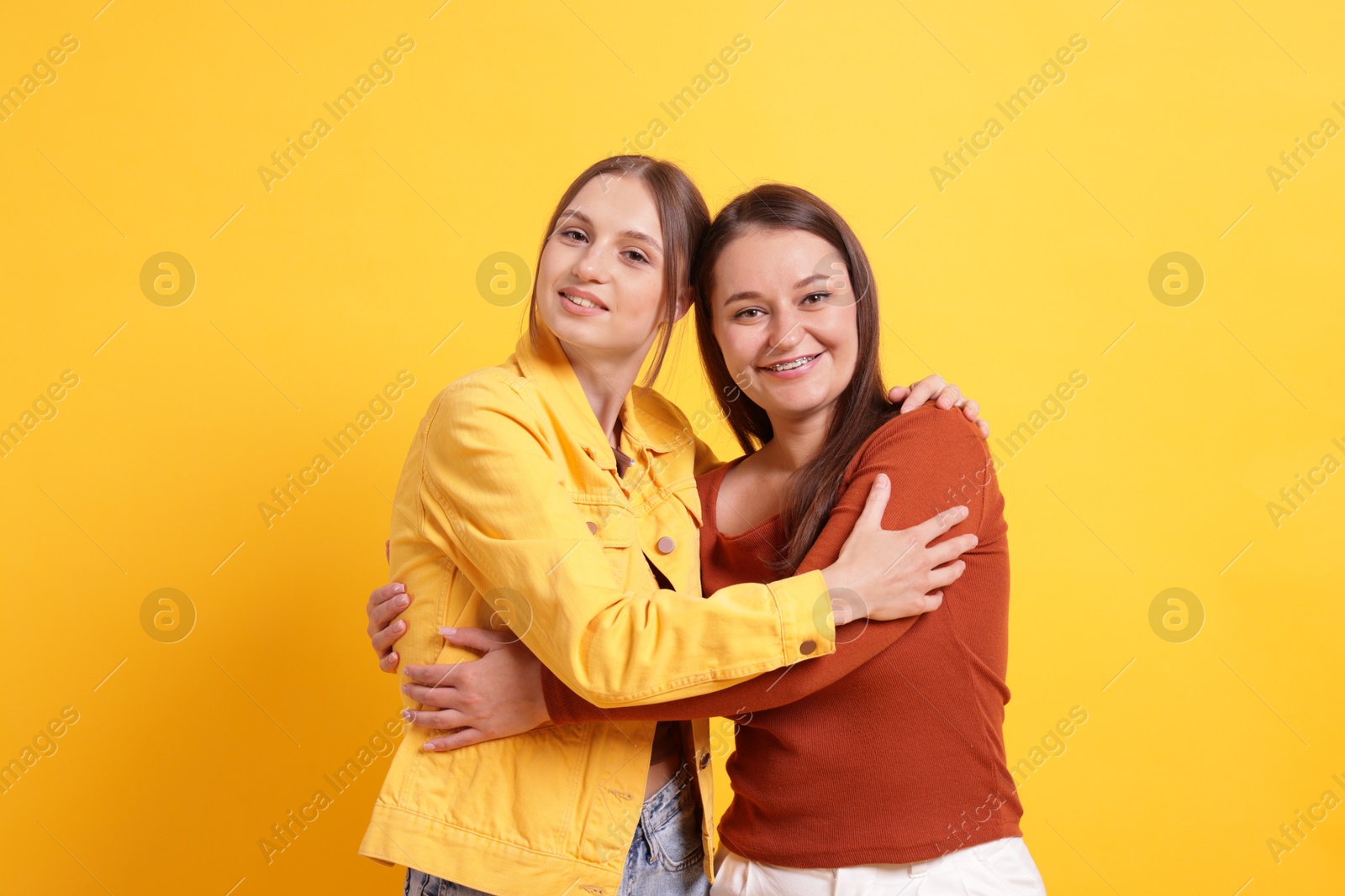 Friends hugging each other on orange background Photo of Friends hugging each other on orange background