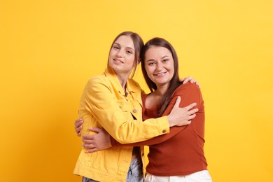 Photo of Friends hugging each other on orange background