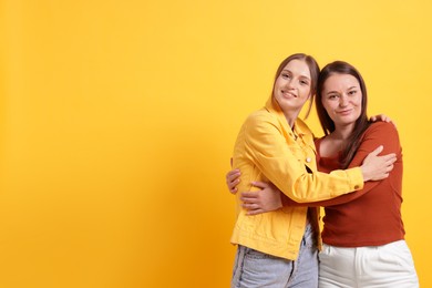 Photo of Friends hugging each other on orange background, space for text