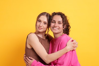 Photo of Friends hugging each other on orange background