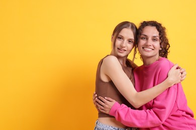 Photo of Friends hugging each other on orange background, space for text