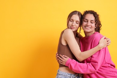 Photo of Friends hugging each other on orange background, space for text
