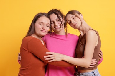 Photo of Friends hugging each other on orange background