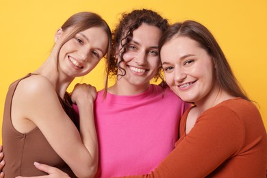 Photo of Friends hugging each other on orange background