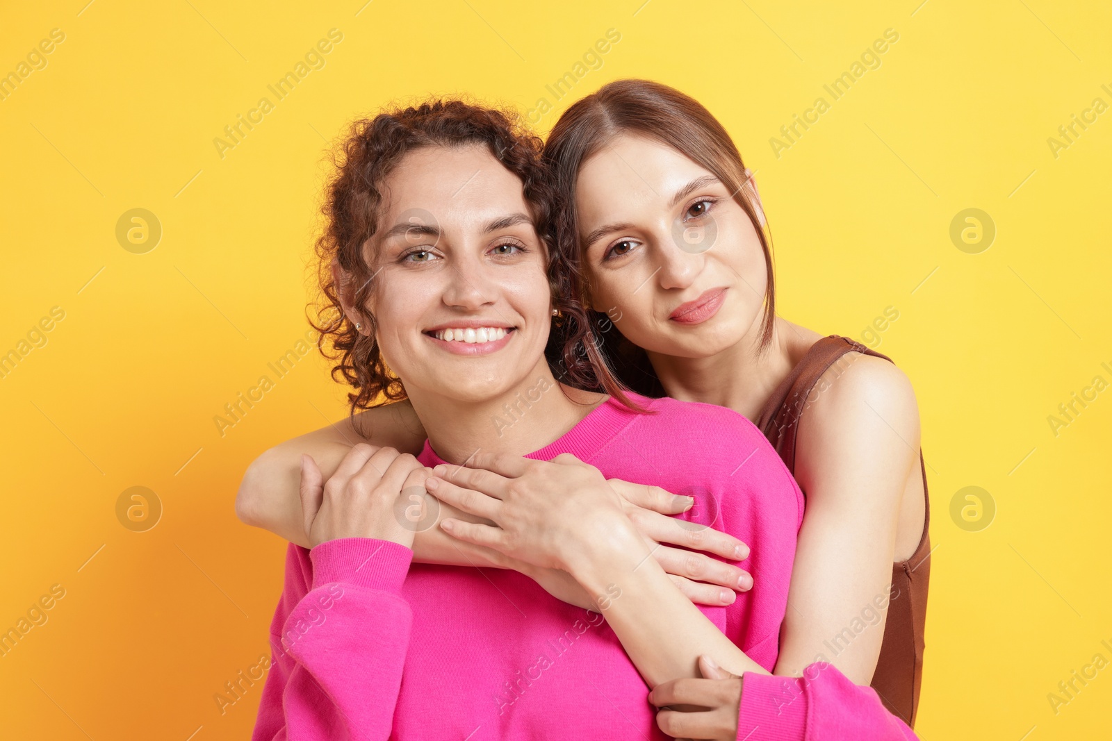 Photo of Friends hugging each other on orange background