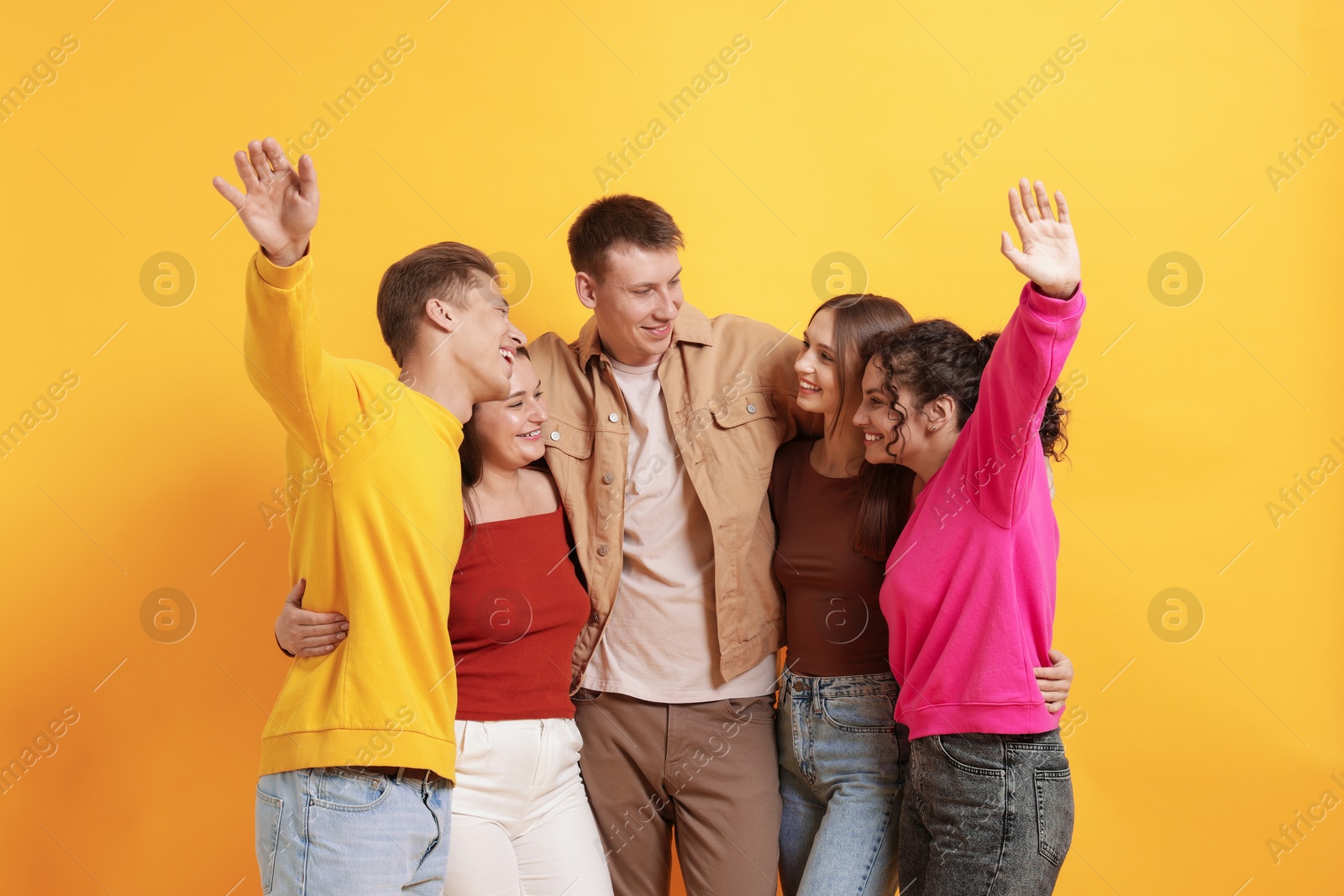 Photo of Group of friends hugging each other on orange background