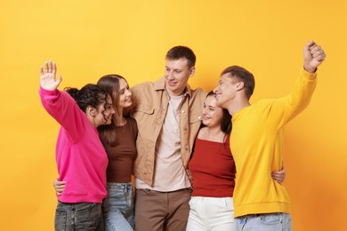 Photo of Group of friends hugging each other on orange background