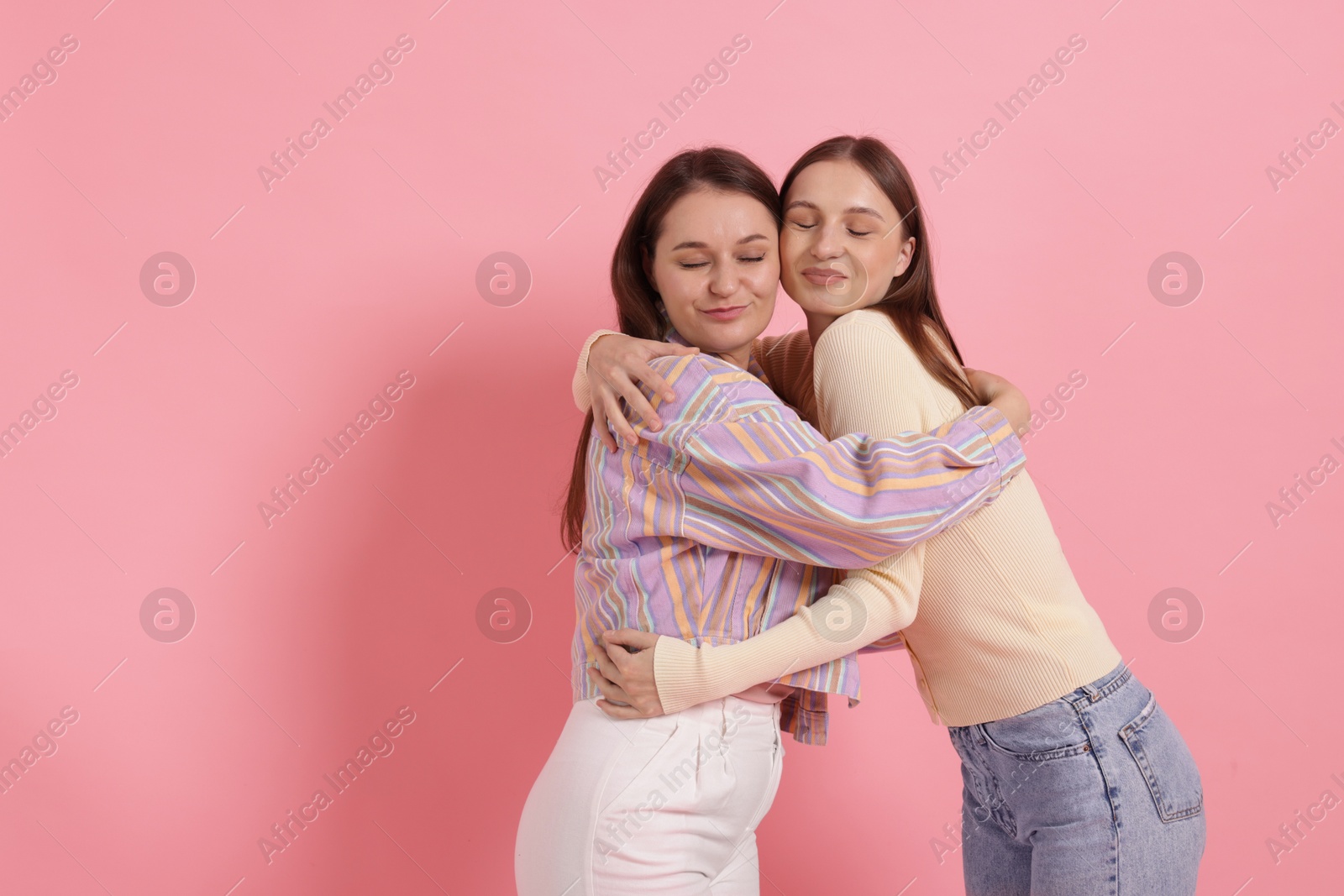 Friends hugging on pink background, space for text Photo of Friends hugging on pink background, space for text